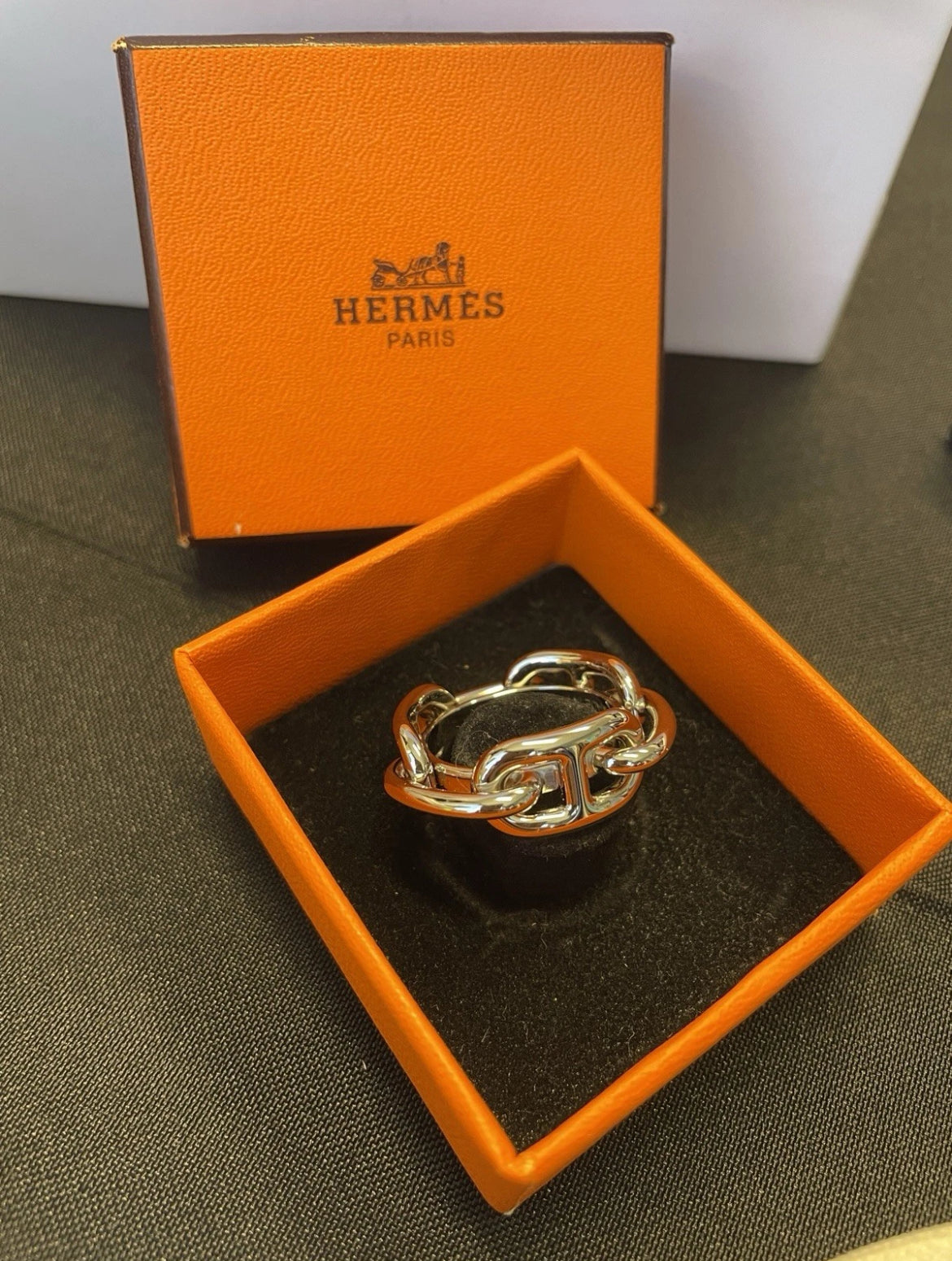 HERMES scarf ring in original orange box with silver finish visible.