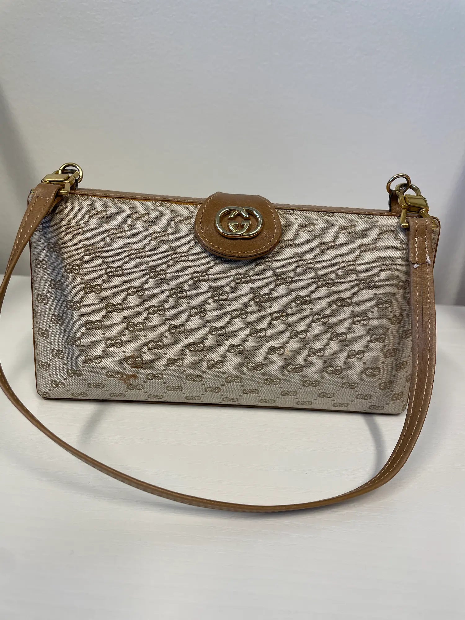 Front view of Gucci GG monogram clutch with structured silhouette.