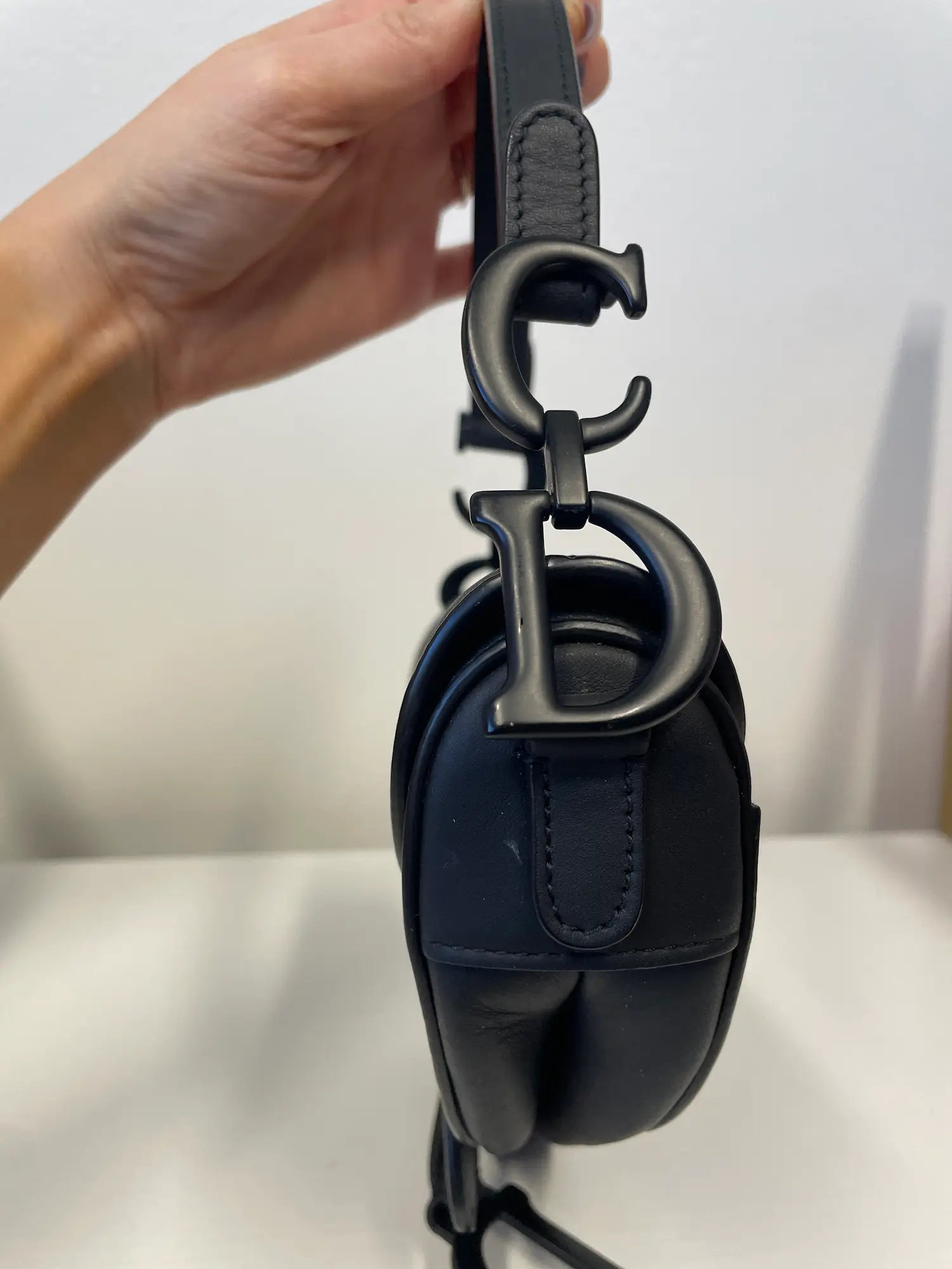 Side view of Dior Saddle Bag showing curved silhouette and matte finish.