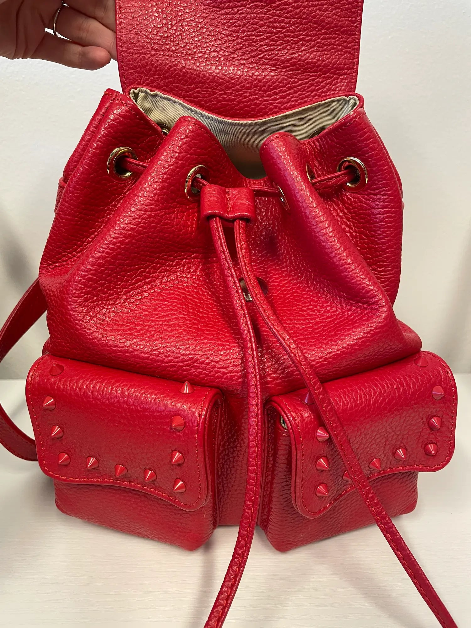 Front view of Valentino red leather backpack showing flap and studs.