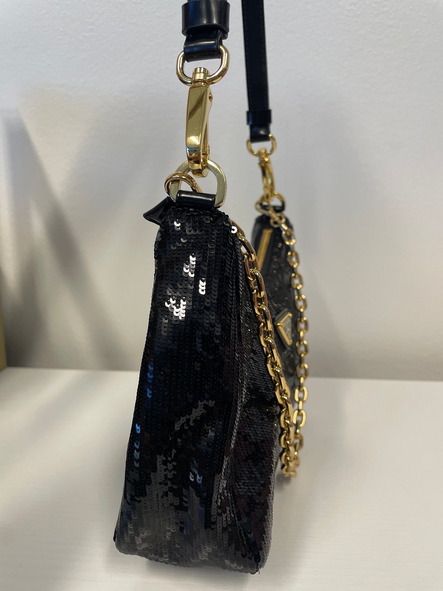 Close-up of Prada enamel triangle logo and sequin detail.